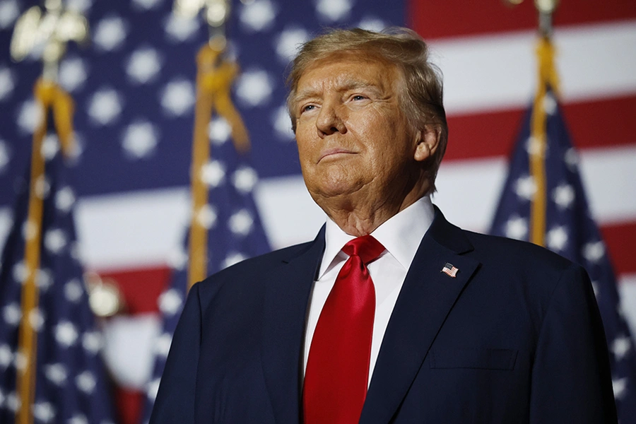 Former President Donald Trump standing at a podium with American flags, celebrating his re-election.