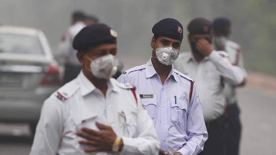 Police personnel manage traffic while wearing masks, highlighting efforts to address pollution control challenges.